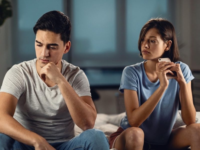 young-worried-man-thinking-something-while-sitting-his-girlfriend-having-relationship-problems-with-her_637285-1976